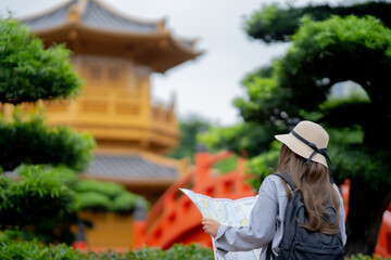 Asian tourist, cute woman with long hair are traveling in Hong Kong along with map and her camera with fun on her holiday, A temple in Hong Kong, concept travel, Nan Lian garden, Chinese classical. 
