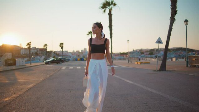 Luxurious girl walking roadway at sunset sunlight. Fashion model strolling road