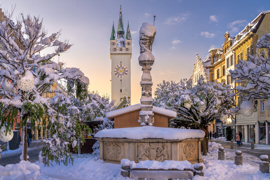 Straubing im Winter mit Schnee auf dem Stadtplatz, Stadtturm und Christkindlmarkt bei blauem Himmel in Niederbayern