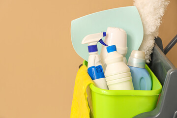 Trolley with cleaning supplies on beige background, closeup