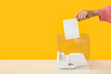 Foto op Plexiglas Hand putting voting paper in ballot box on yellow background © Pixel-Shot