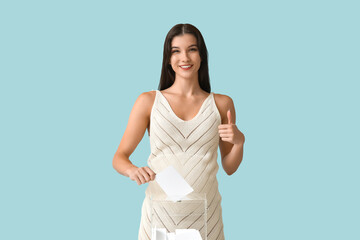 Pregnant woman with voting paper showing thumb-up on light blue background