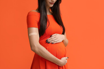 Young pregnant woman after vaccination on orange background