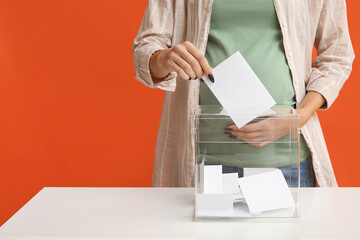 Voting pregnant woman near ballot box on orange background, closeup