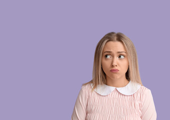 Fototapeta premium Embarrassed young woman on lilac background