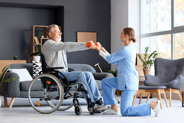 Senior man in wheelchair with dumbbells and nurse training at home