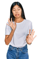 Beautiful young asian woman wearing casual white t shirt disgusted expression, displeased and...