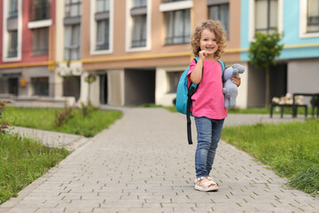 Happy girl with toy walking to kindergarten outdoors. Space for text