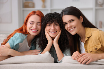 Portrait of happy young friends on sofa at home