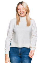 Young caucasian woman wearing casual winter sweater winking looking at the camera with sexy...