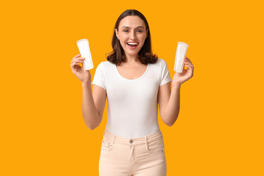 Beautiful young woman with menstrual pads on yellow background