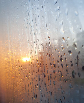 Closeup of Beautiful Rain drop on the window glass after the rain with golden light sunset blurred bokeh background at Thailand.