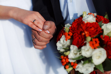 Delicate wedding bouquet in the hands of the bride at the ceremony. Hands of a newly-married couple...