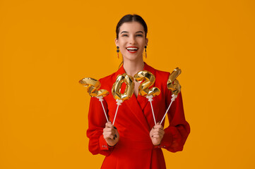 Beautiful young happy woman with figure 2024 made of balloons on yellow background. Chinese New...