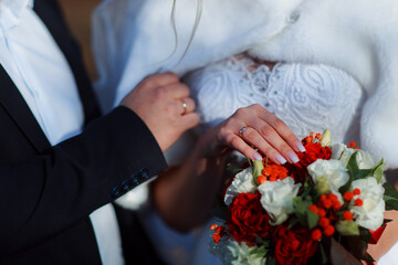Delicate wedding bouquet in the hands of the bride at the ceremony. Hands of a newly-married couple...