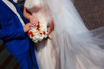 Delicate wedding bouquet in the hands of the bride at the ceremony. Hands of a newly-married couple...