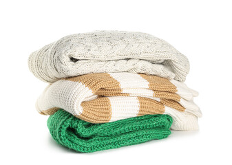 Stack of new different stylish sweaters on white background