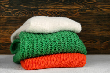 Stack of different stylish sweaters on table