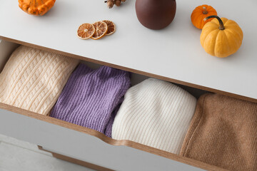 Chest of drawers with different stylish sweaters and pumpkins in room, closeup - obrazy, fototapety, plakaty