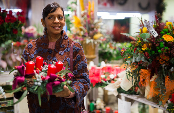 Latin American woman who came to the store for shopping chooses a Christmas composition with candles