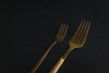 Two metal forks on a black background.