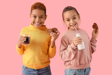Poster Little children eating cookies with hot chocolate and milk on pink background © Pixel-Shot
