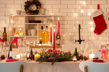 Festive table setting with Christmas decorations and glowing lights in kitchen at evening - obrazy, fototapety, plakaty