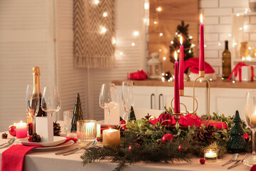 Festive table setting with Christmas decorations and glowing lights in kitchen at evening, closeup