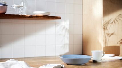 A sunny kitchen with white tile walls, a wooden table and sink.