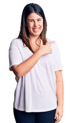 Fototapeta premium Young beautiful brunette woman wearing casual t-shirt cheerful with a smile of face pointing with hand and finger up to the side with happy and natural expression on face