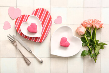 Beautiful table setting with roses and cakes for Valentine's Day on white tile background