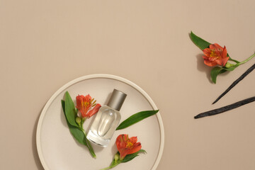 Top view of fresh flower and green leaves decorated with vanilla sticks on beige background. A round dish container glass perfume bottle without label for design