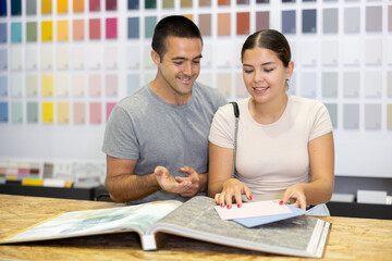 Obraz premium In store, married couple buyer look at product catalog and choose unique color of paint, wall coverings in apartment. Repair and construction items, paint and varnish product, accessories, hypermarket