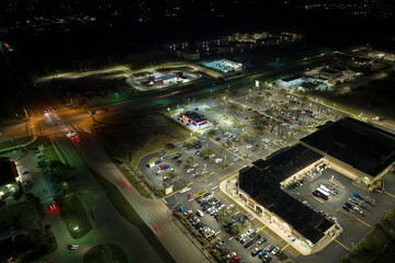 Fototapeta na wymiar Aerial view of large parking lot at nighttime with many parked cars. Dark carpark at supercenter shopping mall with lines and markings for vehicle places and directions