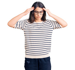 Brunette teenager girl wearing casual clothes and glasses with hand on head for pain in head because stress. suffering migraine.