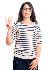 Brunette teenager girl wearing casual clothes and glasses showing and pointing up with fingers number three while smiling confident and happy.