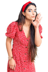 Brunette teenager girl wearing summer dress hand on mouth telling secret rumor, whispering malicious talk conversation