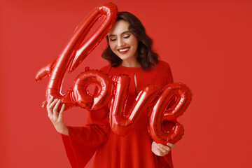 Young woman with air balloons in shape of word LOVE on red background