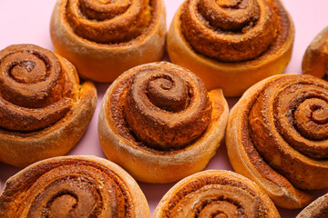Tasty cinnamon rolls on lilac background