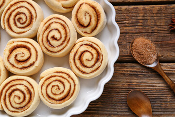 Obraz na płótnie Canvas Baking dish with uncooked cinnamon rolls on wooden background