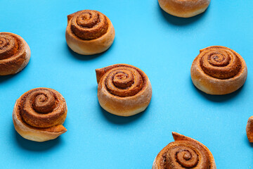 Tasty cinnamon rolls on blue background