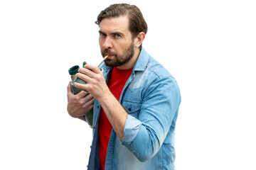 Young man drinking mate, holding the thermos in one arm.