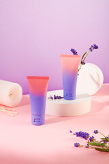 Close-up of two cosmetic tubes standing out on a pink-purple background with a white podium and fresh lavender. Lavender essential oil helps reduce skin irritation and promote skin recovery.