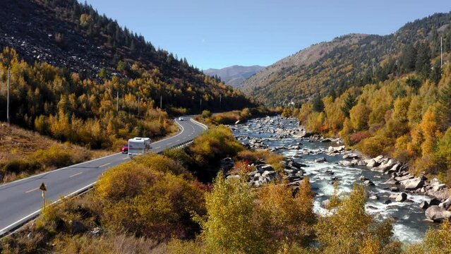 Campervan drives along scenic autumn highway by river in Xingdu Qiao Jia Genba Tibetan Sichuan Western China