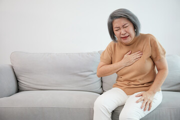 senior woman pain suffering from heart disease on sofa