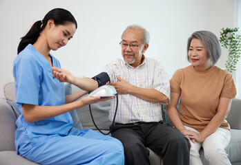 caregiver or nurse measure blood pressure to senior man on sofa