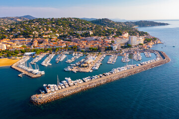 Summer aerial view of French coastal town of Sainte-Maxime on Mediterranean coast overlooking marina with moored pleasure yachts and residential houses on green hills