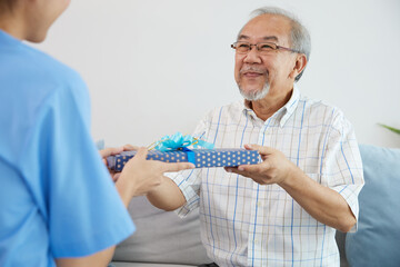 senior man giving present or gift from caregiver for happy birthday