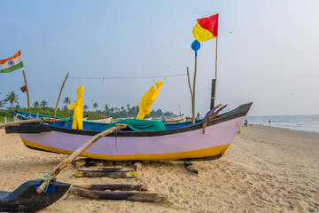 Fototapeta premium old fishing boats in sand on ocean in India on blue sky background