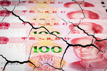 Destruction China economy. Yuans banknotes with cracks.